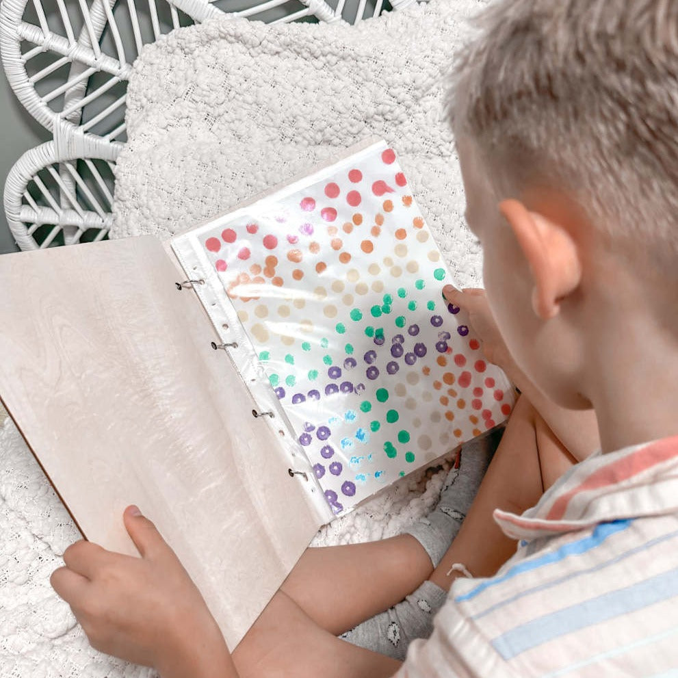 Open Wild Daisy children's art binder showing plastic sleeve storage — holds up to 50 artworks