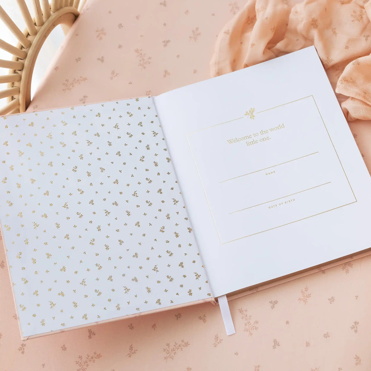 Open baby book with gold dot pattern on a soft pink background