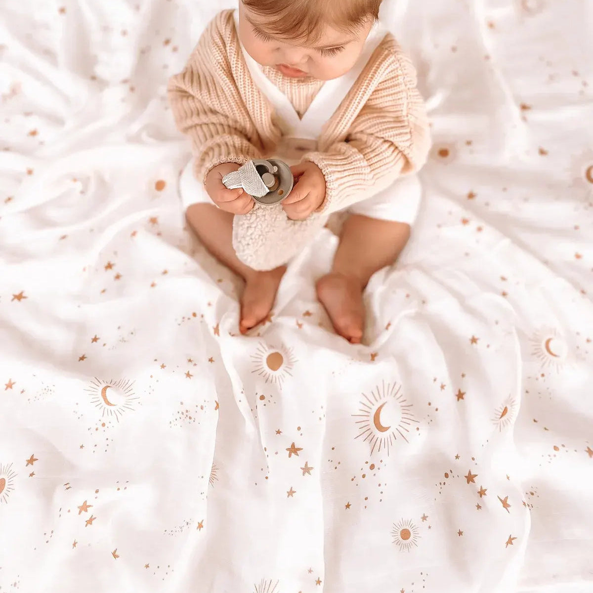 Baby sitting on an extra large organic muslin swaddle with
constellation print
