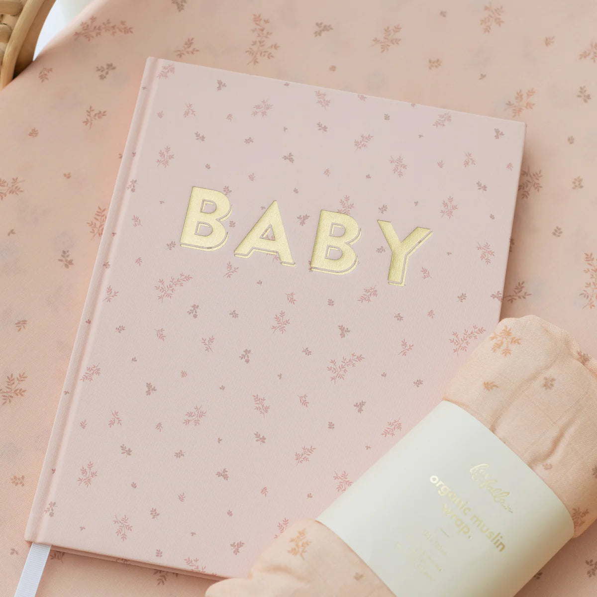 Wild Ruscus swaddle beside a
pink BABY memory book, newborn gift set