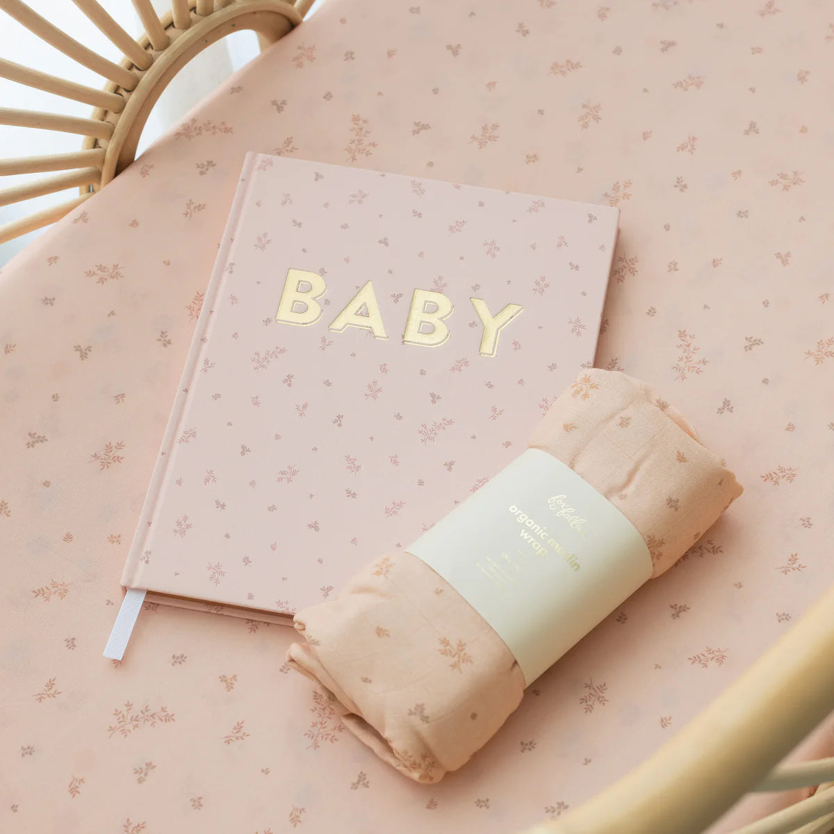 Wild Ruscus muslin swaddle and matching pink BABY
journal styled in a rattan bassinet
